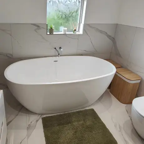 Large marble tiles surround in bathroom with roll top bath