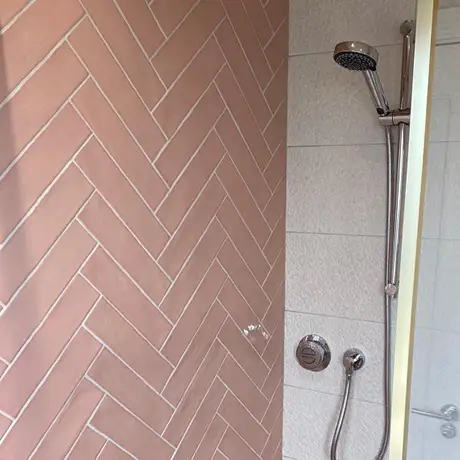 Pink tiles in herringbone design on shower wall