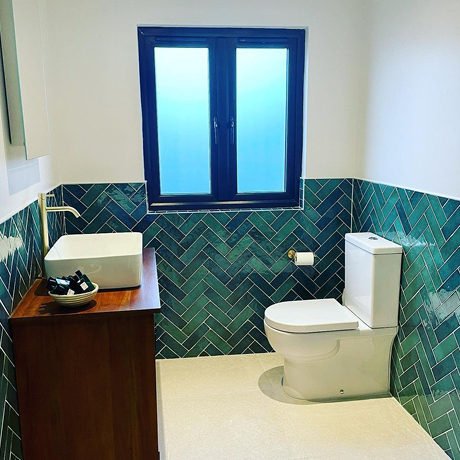 Emerald green herringbone half tiled bathroom wall