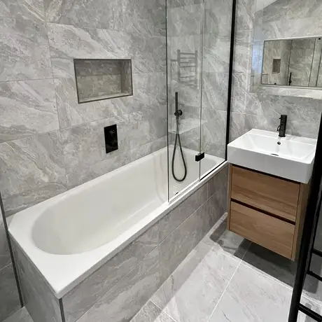 Grey marble fully tiled bathroom with black taps