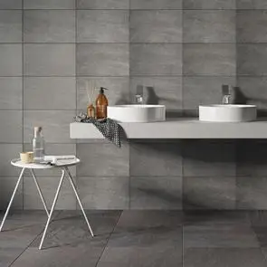 450x450 Fairford dark grey tile in a open plan bathroom with wall mounted his and her sinks and freestanding table