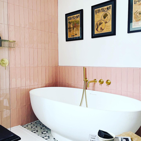 Vertical pink tiles and white roll-top bath