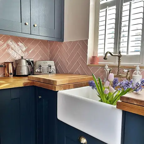 Pink herringbone kitchen splashback with navy units