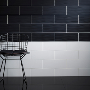 Gloss black tiles on the floor of the room whilst black and white rectangular tiles cover the wall.