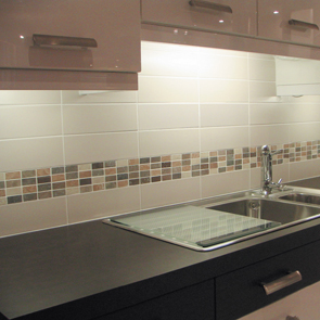 Cream wall tile worked together with brown shaded mosaic tiles on wall of kitchen.  