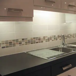 Cream wall tile worked together with brown shaded mosaic tiles on wall of kitchen.  