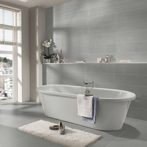 Stone by stone brown tile in a large bathroom setting with cream rug and freestanding curved bath,