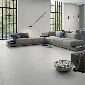 Large open plan living room with grey low to ground couch, fully tiled in the stone by stone beige 450x450 tile.