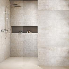 Handcrafted beige décor tile on a back wall of a shower enclosure with complimenting plain tiles
