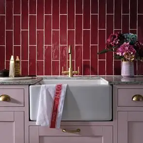 Traditional kitchen with pink units with gold handles. Poitiers bordeaux tiles in a vertical brick bond pattern