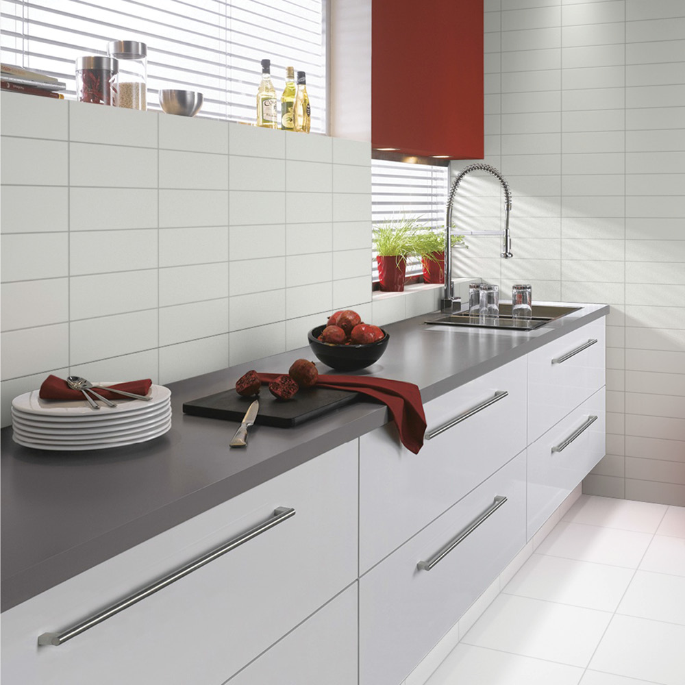 White wall tiles with matching floor tiles in a modern kitchen area.
