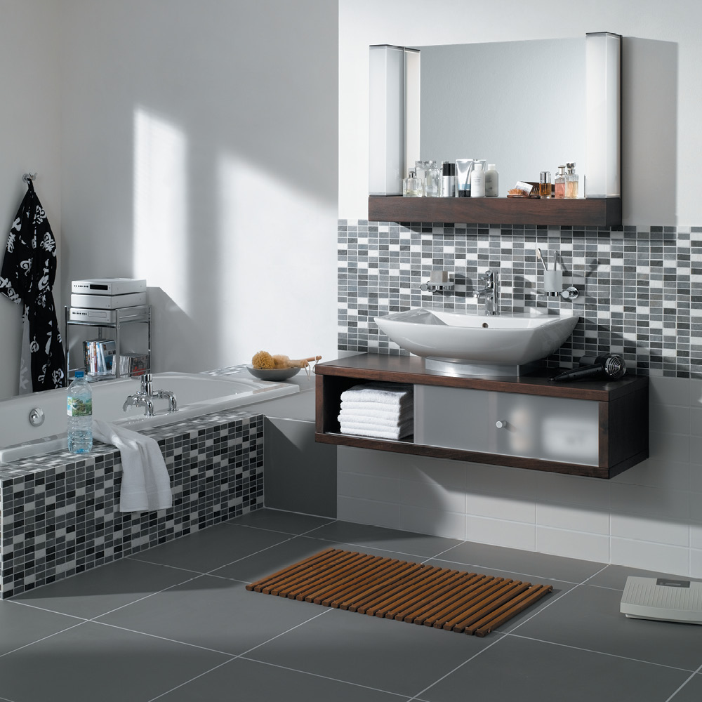 Large format grey floor tiles partnered with grey mosaic tiles on the walls of a bathroom.
