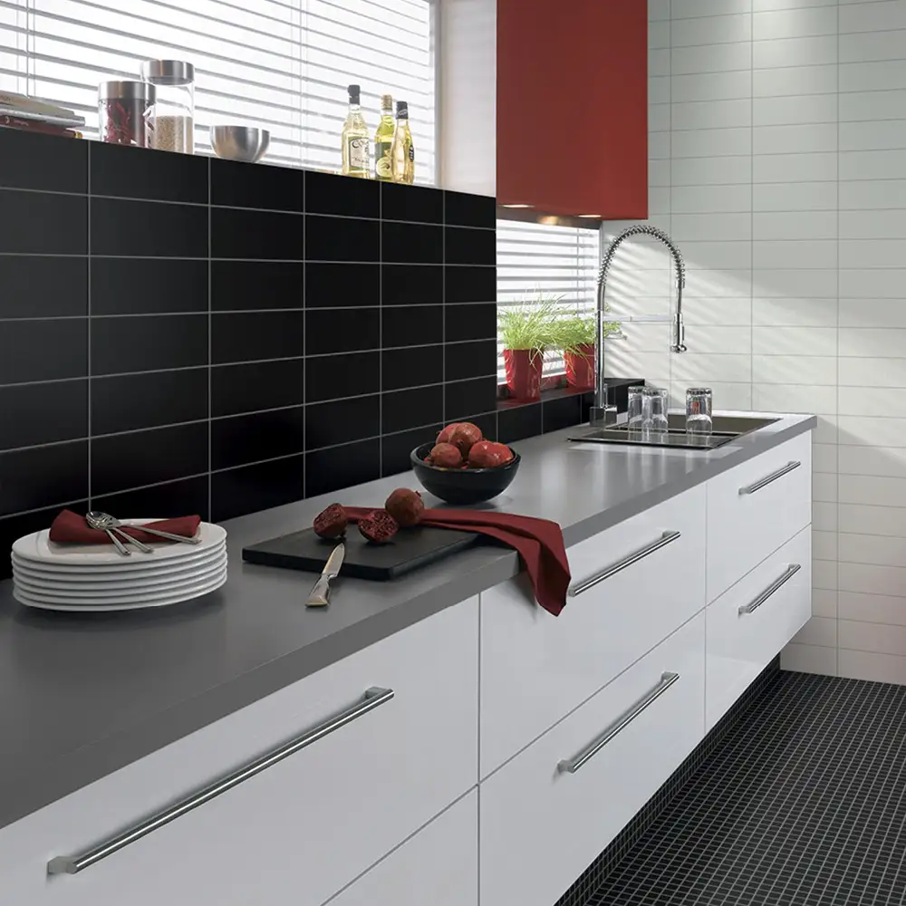 Black mosaic style floor tiles and black and white wall tiles in a new modern kitchen. 