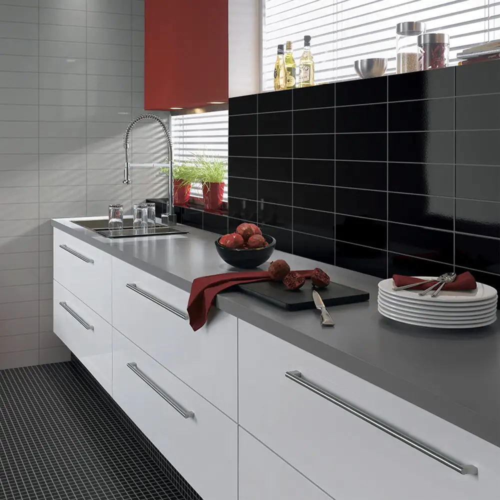 Gloss white kitchen units and grey counter tops with step gloss black tiles above with white accenting tiles