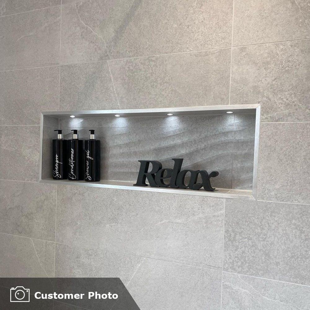 Rock grey tile in a bathroom setting with built in niche and down lights with Black accessories.