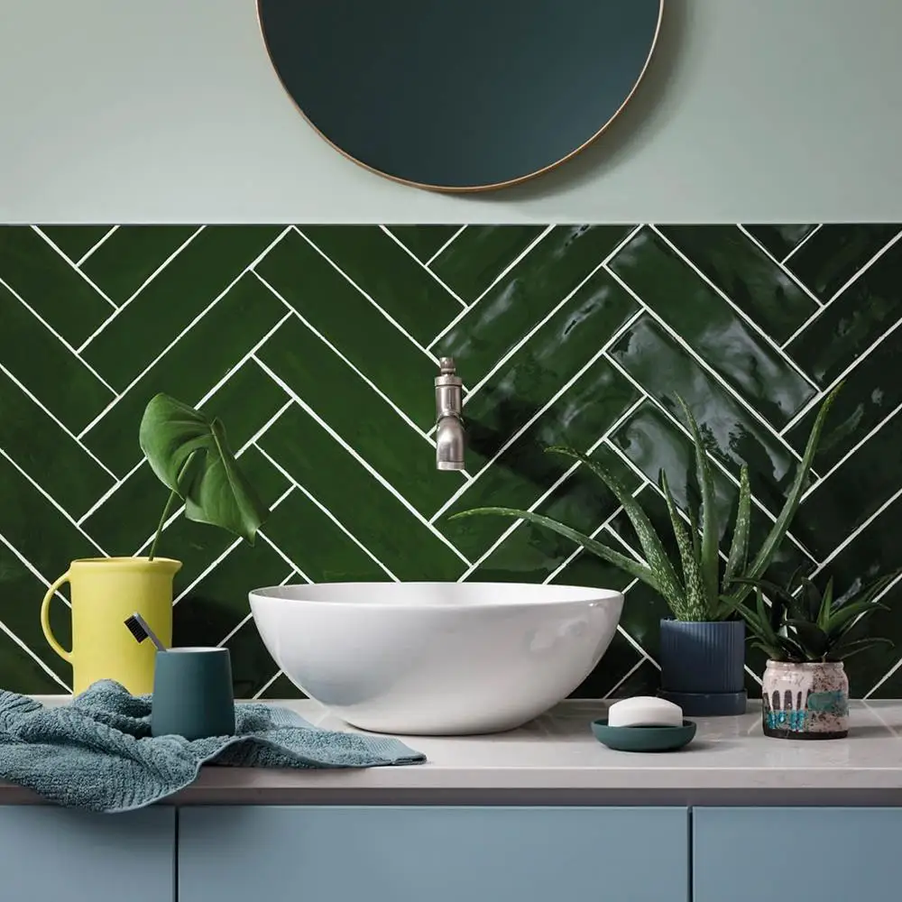 half tiled bathroom wall with herringbone indigio green poitiers tiles, with wall mounted tap and freestanding sink.